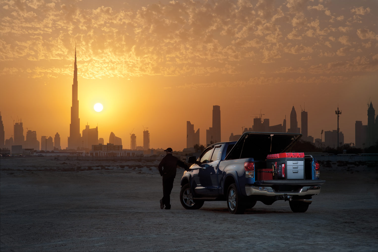 Niebieski pick-up z regałami modułowymi na pustyni podczas zachodu słońca